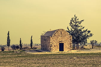 Rustic stone chapel in hazy yellow countryside landscape