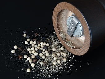 Wooden Pepper Mill with Spilled White and Black Peppercorns