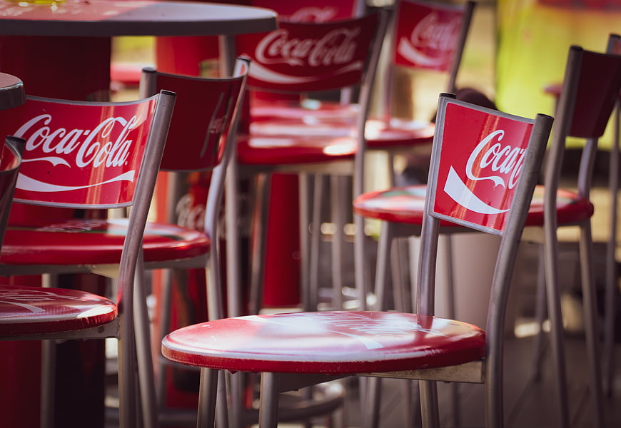 Red Coca-Cola Branded Chairs At Outdoor Cafe Table