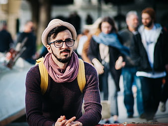 Hipster man with glasses and scarf in urban crowd