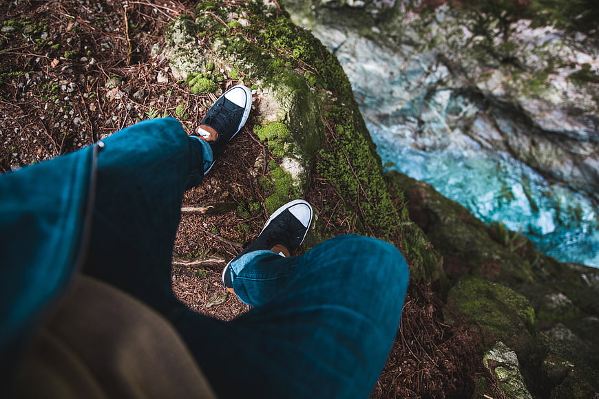 First-person view of hiker standing on mossy cliff edge
