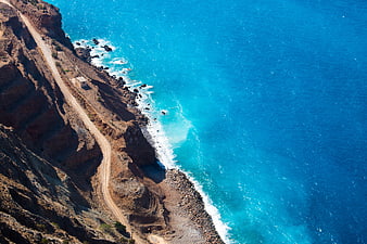 Aerial View of Winding Coastal Road Along Blue Ocean Cliffs