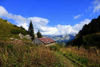 Rustic Mountain Cabin in Alpine Landscape with Blue Sky