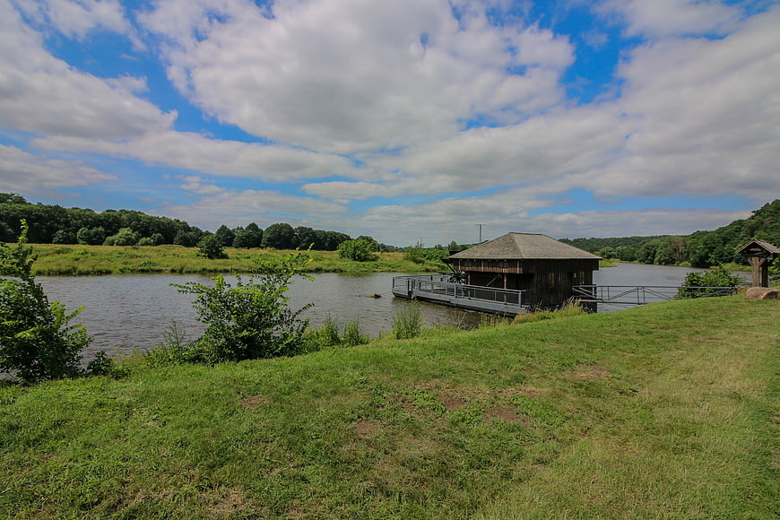 Rural wooden water mill on a calm river with green grass