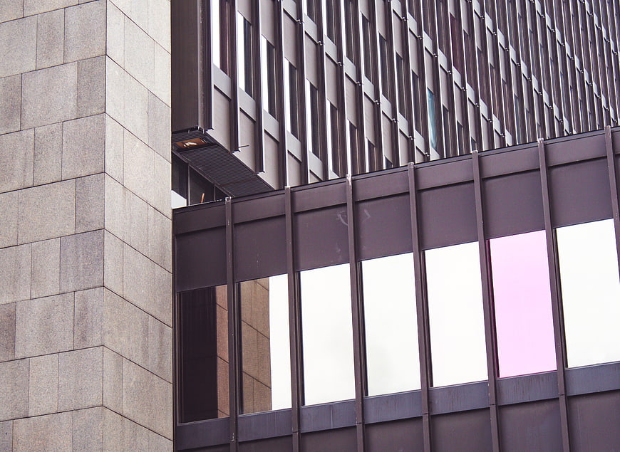Modern building facade with geometric patterns and pink window reflection