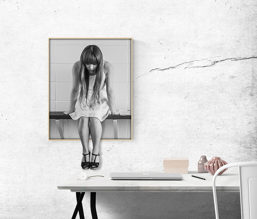 Sad woman sitting on bench in black and white framed art