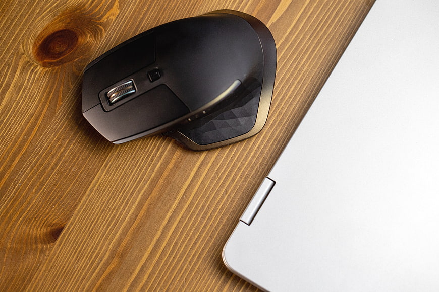 Black Wireless Mouse and Silver Laptop on Wooden Desk
