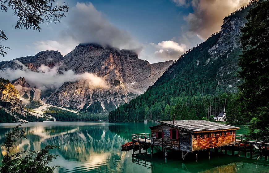Serene Alpine Lake with Wooden Boathouse and Mountain Reflections