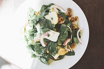 Overhead shot of fresh spinach salad with walnuts and cheese