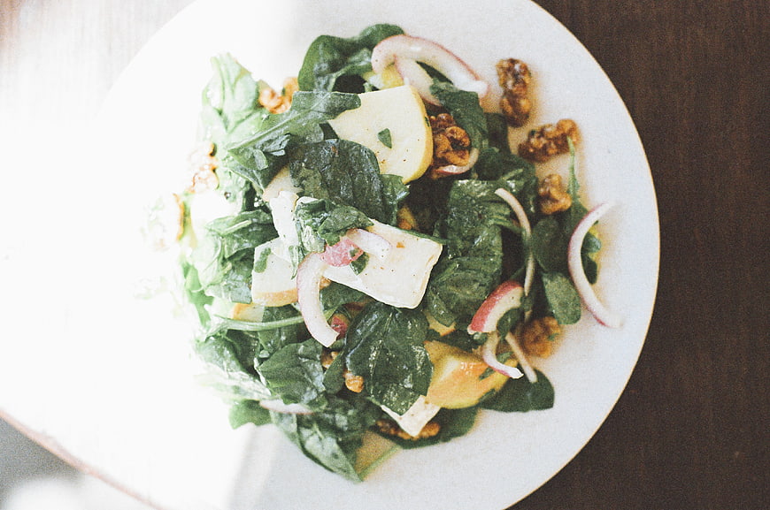 Overhead shot of fresh spinach salad with walnuts and cheese