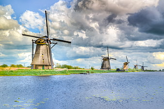 Traditional Dutch Windmills Along Canal Under Dramatic Sky