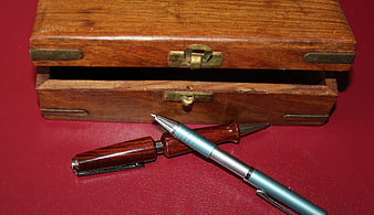 Vintage wooden box with compass and pen on red background