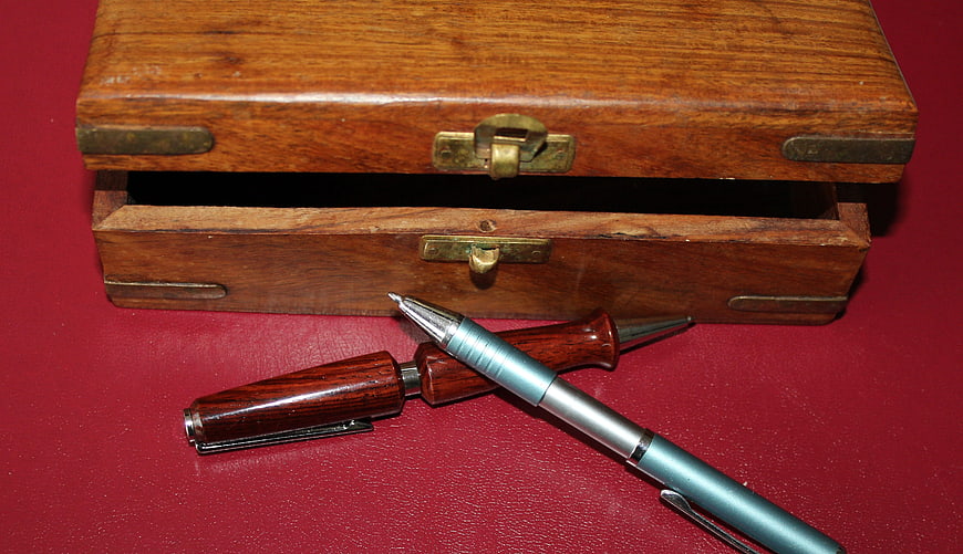 Vintage wooden box with compass and pen on red background