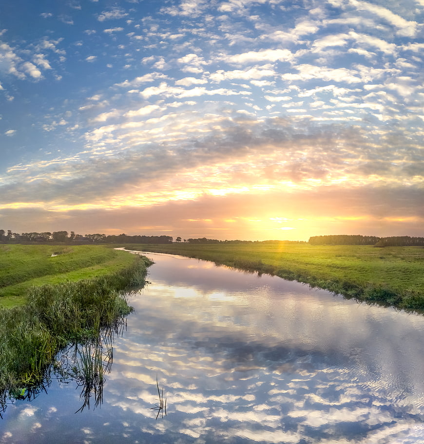 Serene River Landscape with Golden Sunset and Cloud Reflections
