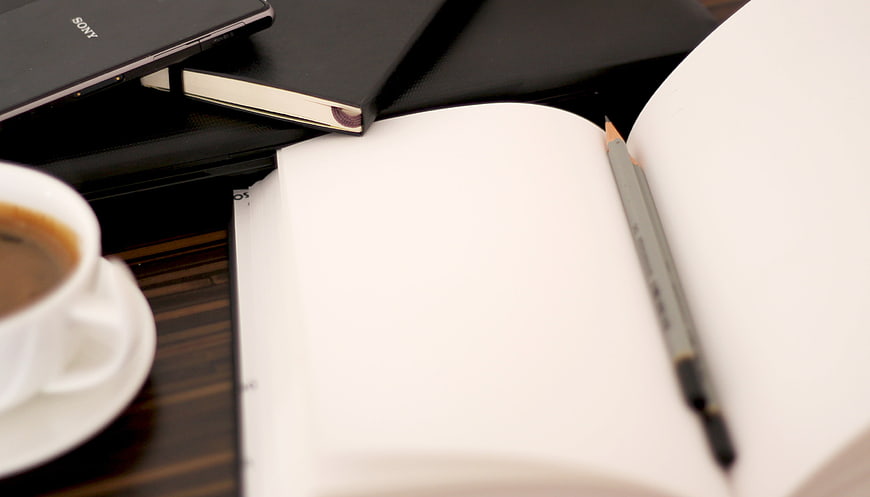 Open Notebook, Pen, Coffee, and Laptop on Dark Wooden Desk