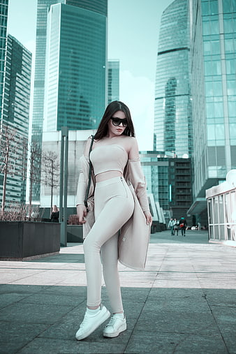 Fashionable woman in beige outfit posing in modern city