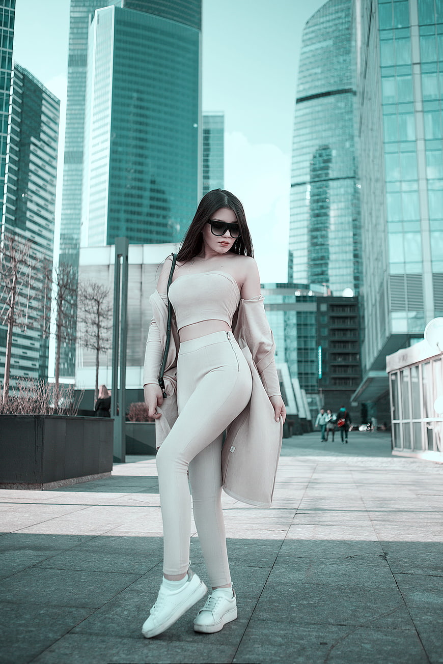 Fashionable woman in beige outfit posing in modern city