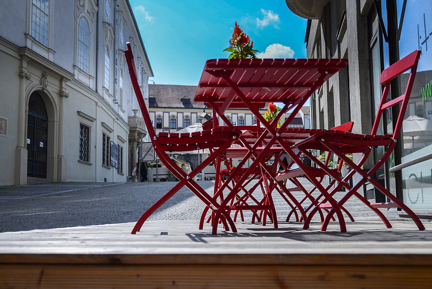 Red Bistro Chairs on Wooden Terrace in European Street