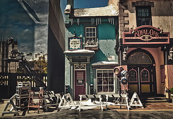 Behind the scenes of a film set with a colorful pub facade and camera crane