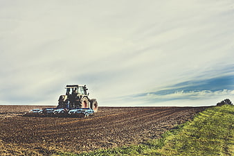 Tractor tilling a field under a cloudy sky