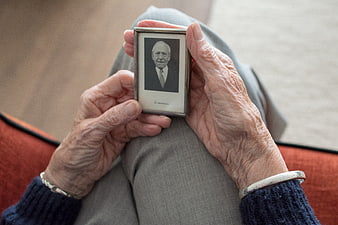 Elderly woman holding framed black and white portrait of deceased man