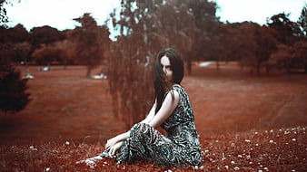 Woman in Patterned Dress Sitting in Red-Tinted Field