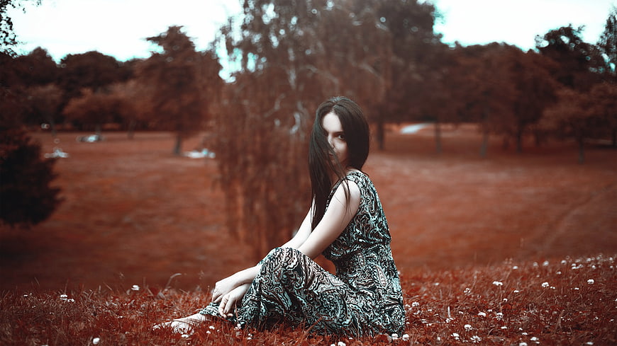 Woman in Patterned Dress Sitting in Red-Tinted Field