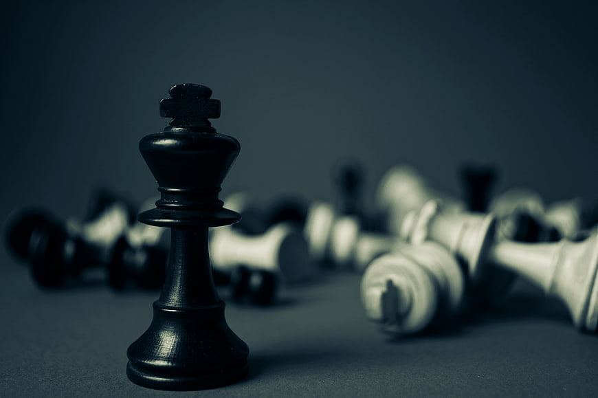Black Chess King Standing Amidst Fallen White Pieces
