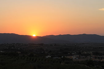 Sunset over mountain range and rural valley landscape