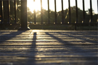 Sunlight and shadows on a wooden deck railing at sunset