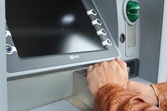 Close-up of hands entering PIN on ATM keypad