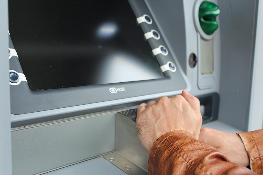 Close-up of hands entering PIN on ATM keypad