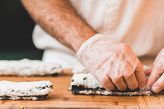 Chef Hands Making Sushi Rolls on Wooden Board