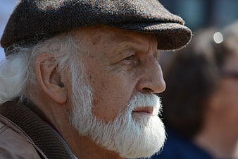 Close-up portrait of elderly man with white beard and flat cap