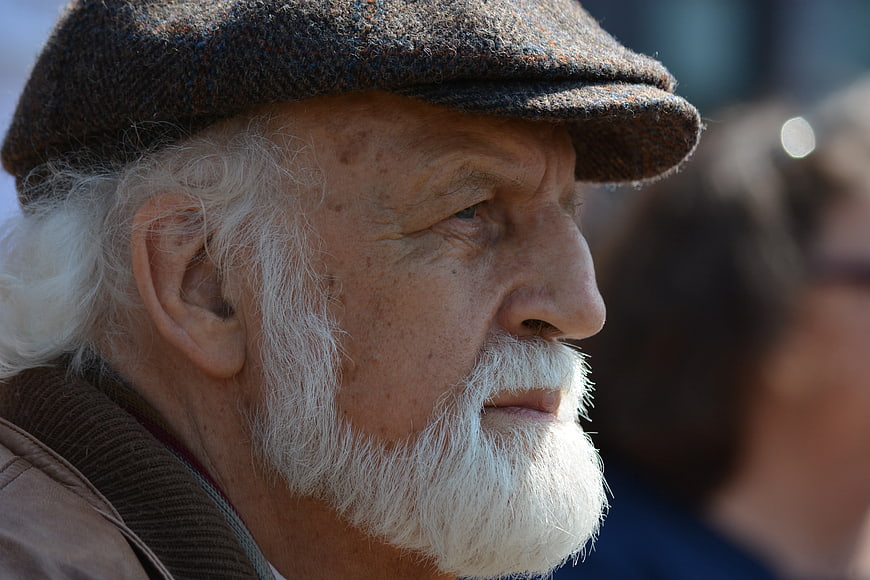 Close-up portrait of elderly man with white beard and flat cap