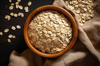 Top View of Rolled Oats in Wooden Bowl on Dark Table
