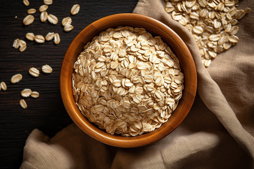Top View of Rolled Oats in Wooden Bowl on Dark Table