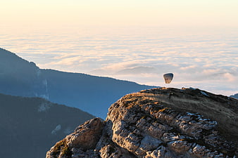Paraglider launching from mountain peak above sea of clouds
