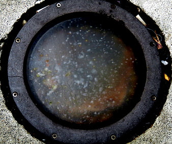 Top view of dirty circular manhole cover with debris