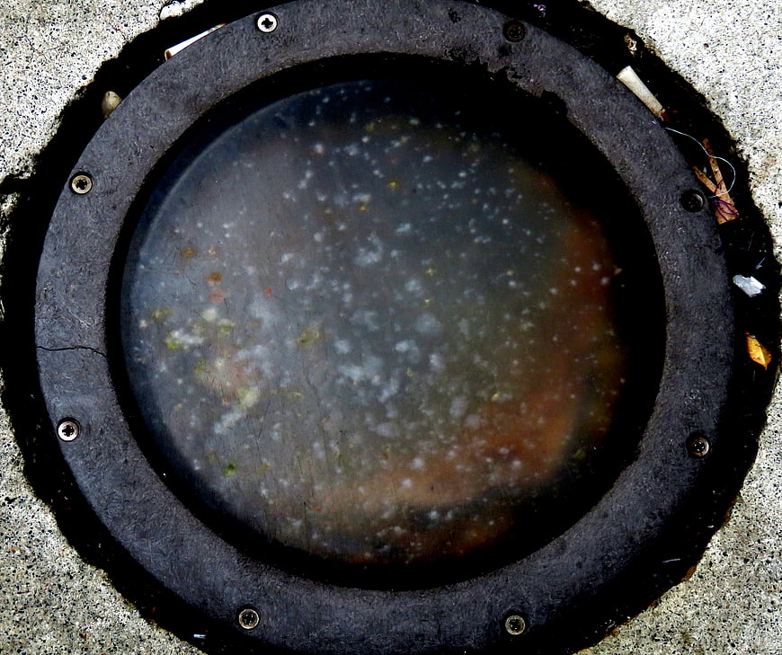 Top view of dirty circular manhole cover with debris