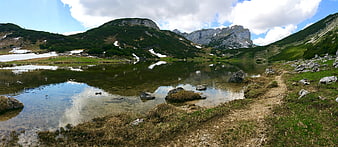 Panoramic Alpine Lake with Mountain Reflections and Snow Patches