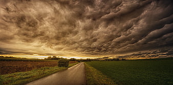 Dramatic Storm Clouds Over Rural Road at Sunset