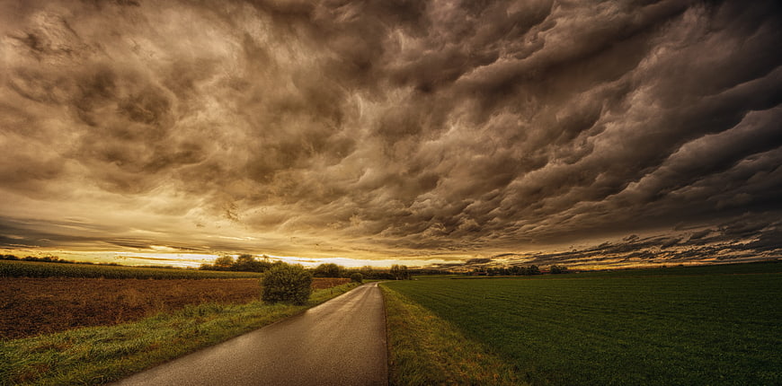 Dramatic Storm Clouds Over Rural Road at Sunset