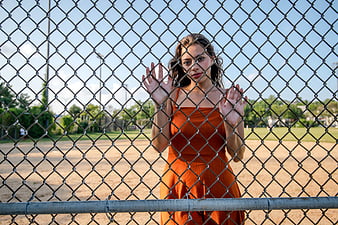 Woman in Orange Dress Behind Chain Link Fence