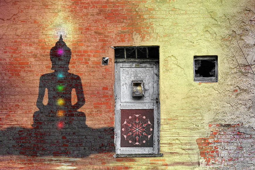 Buddha silhouette with chakras on textured brick wall