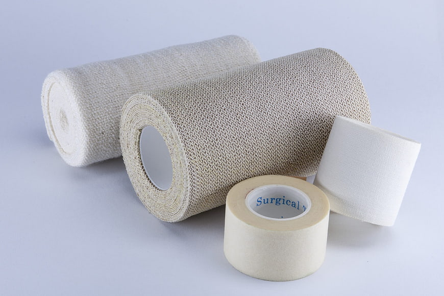 Medical bandages and surgical tape rolls on white background