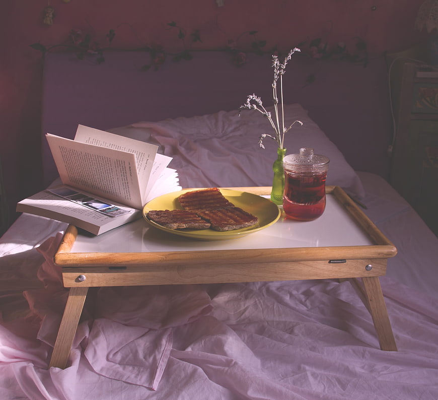 Cozy breakfast in bed with toast, tea, and book