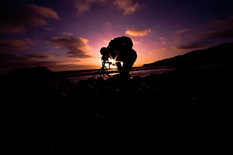 Silhouette of Photographer Capturing Sunset on Rocky Beach