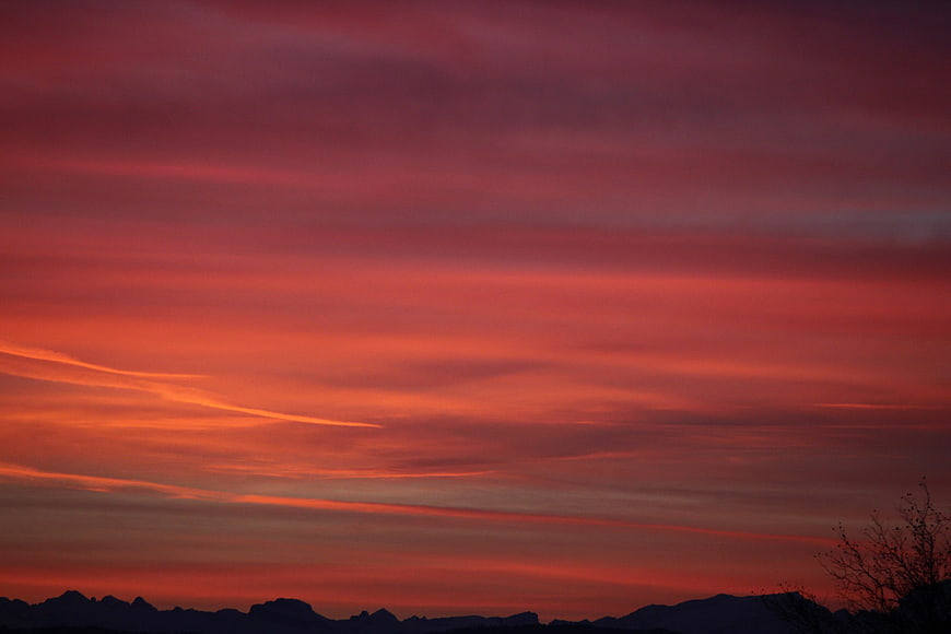Vibrant Red and Orange Sunset Sky Over Mountain Silhouette