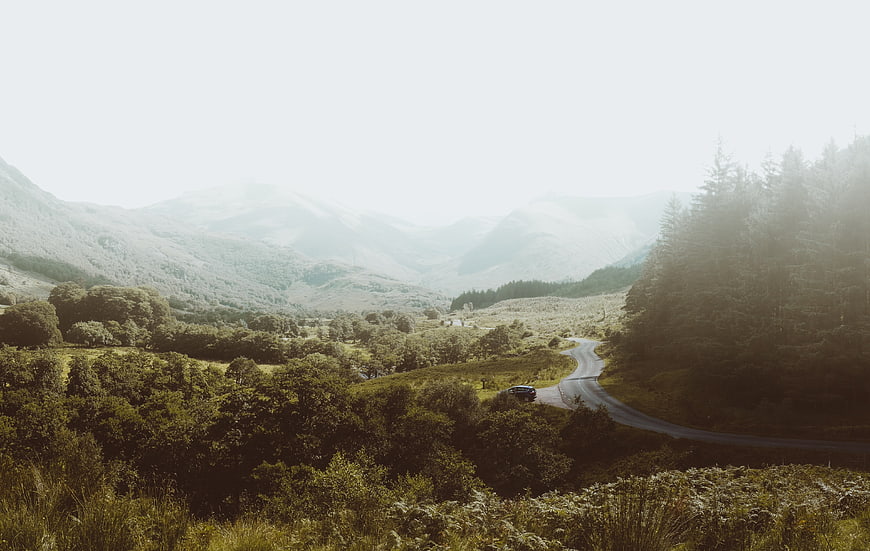 Winding road through misty mountain valley with car